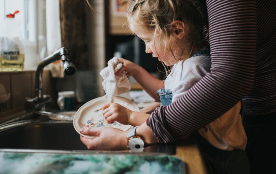 Cute little girl helping a grown up do the dishes