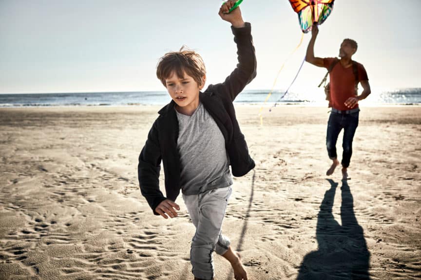 Father and son flying kite on the beach