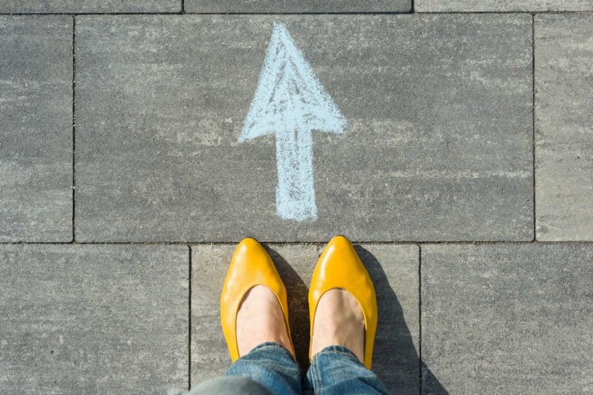 Female feet with arrow painted on the asphalt