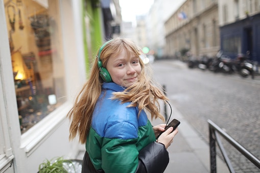 adolescent girl listening to music while walking down the street
