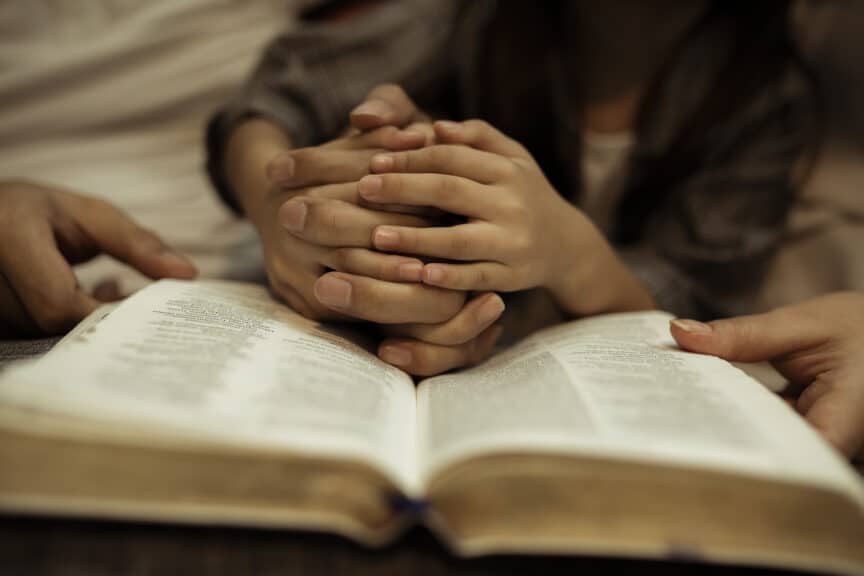 family holding hands over bible