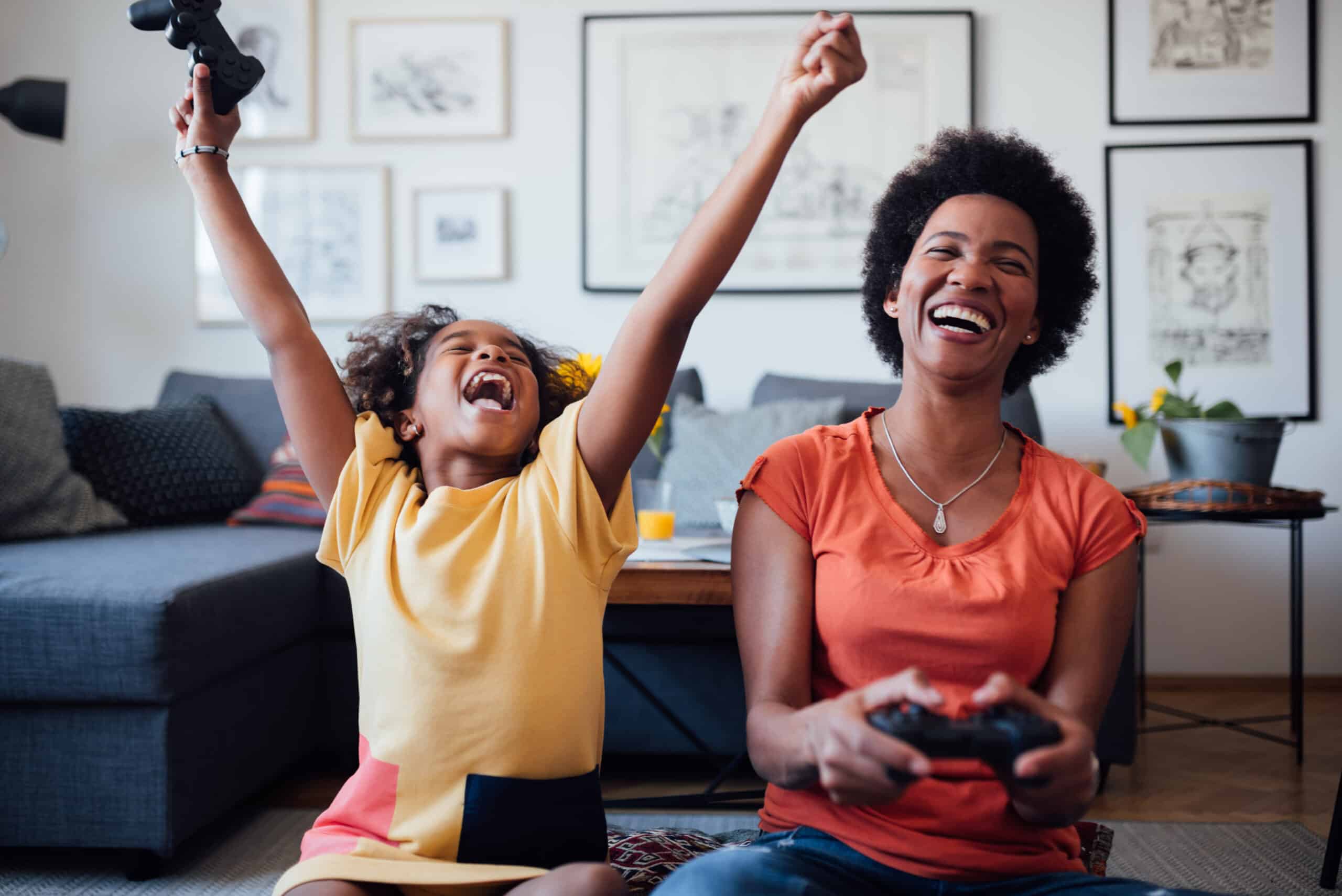 african american mother and daughter playing video games