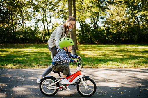 mom helping son learn to ride bike