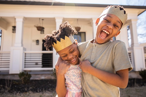 brother and sister smiling with crowns on