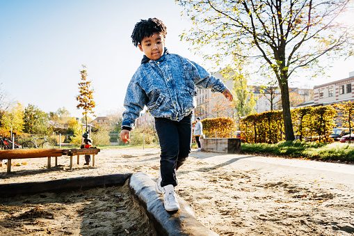 young boy walking across log