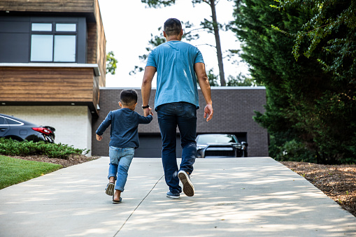 Father walking up driveway with son