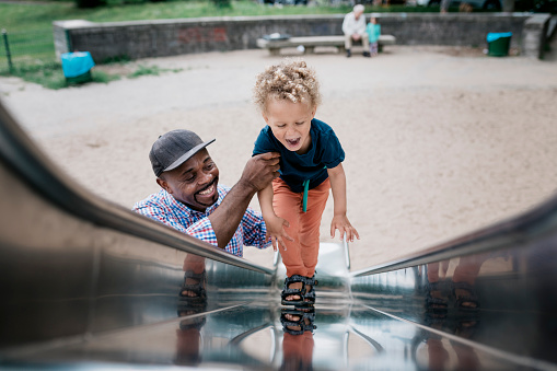 Dad helping his son climb up slide