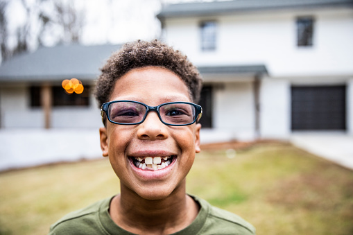 tween boy smiling in front of house
