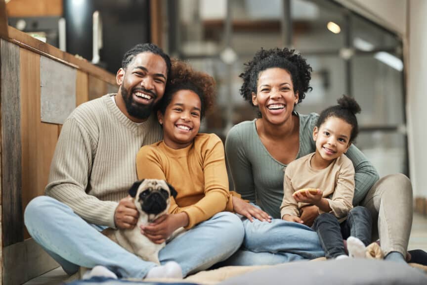 Happy African American family and their dog sitting on the floor at home