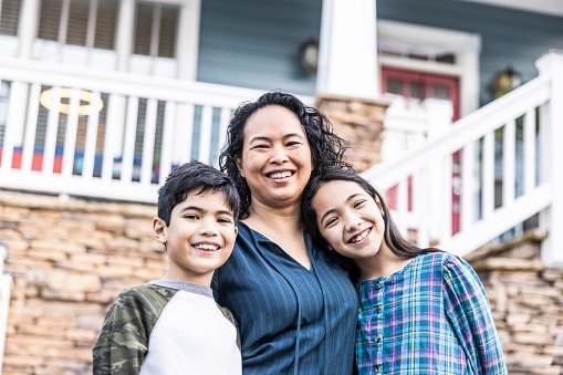 mother and her two kids in front of their house