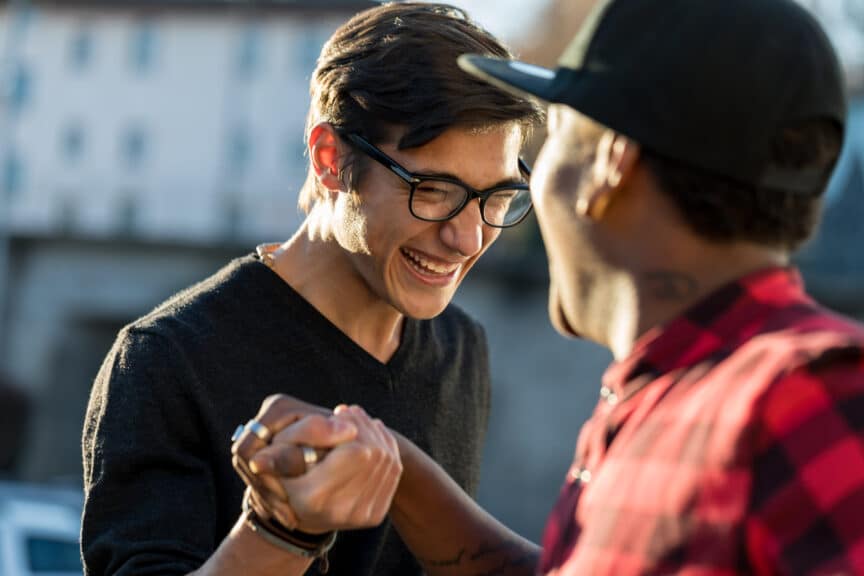 two male friends laughing as they shake hands