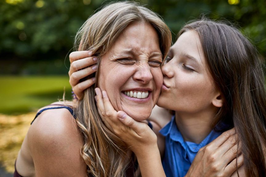 Girl hugging and kissing happy mother