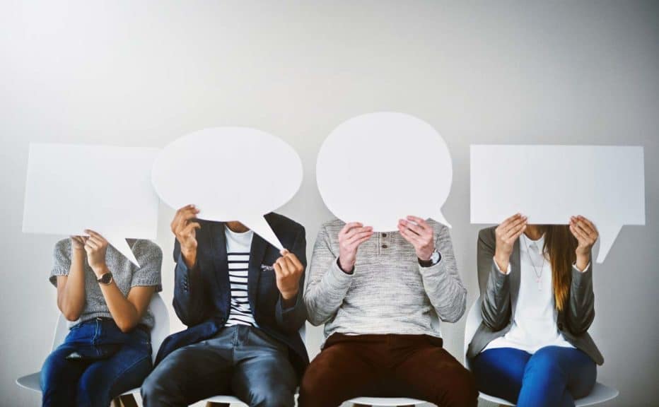 Diverse group of businesspeople holding up speech bubbles while they wait in line