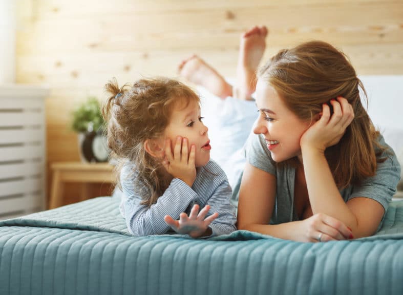 Happy family mother and child daughter laughing in bed