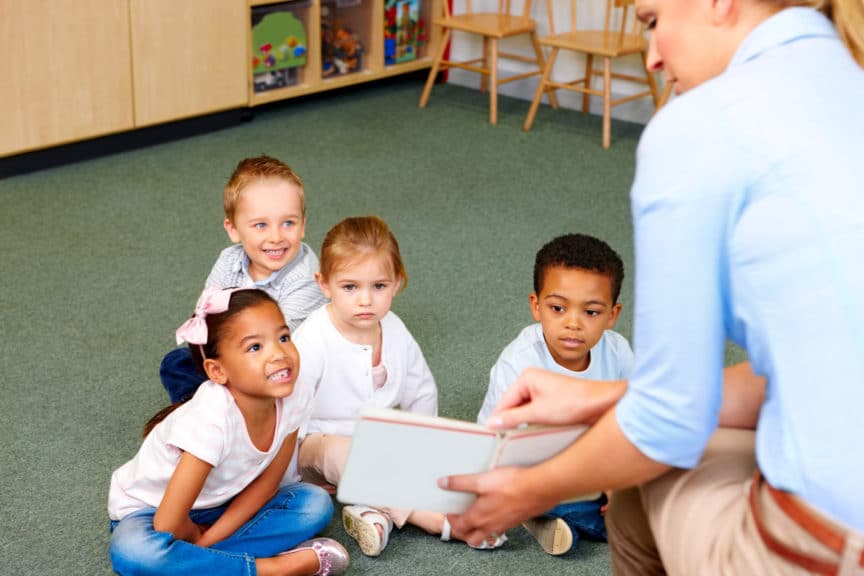 Kindergarten teacher in class reading to students