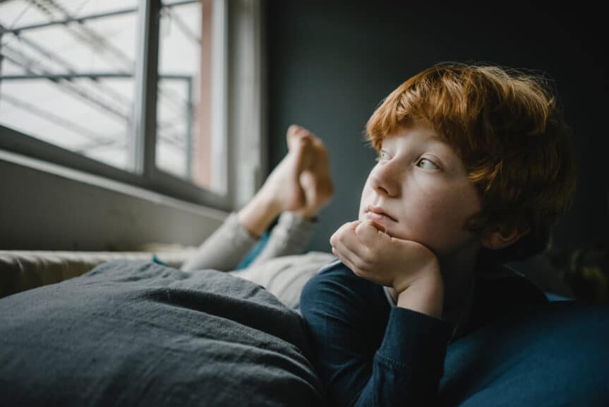 Portrait of redheaded boy lying on couch out of window