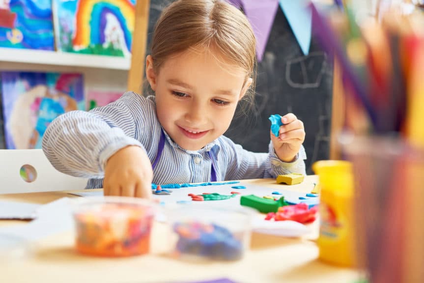 Portrait of smiling little girl working with plasticine in art and craft class