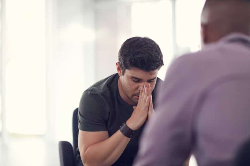 Shot of an unhappy young man talking with a colleague