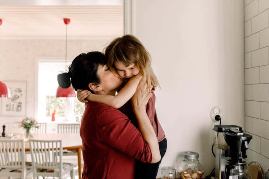 Side view of mother kissing sad daughter at home