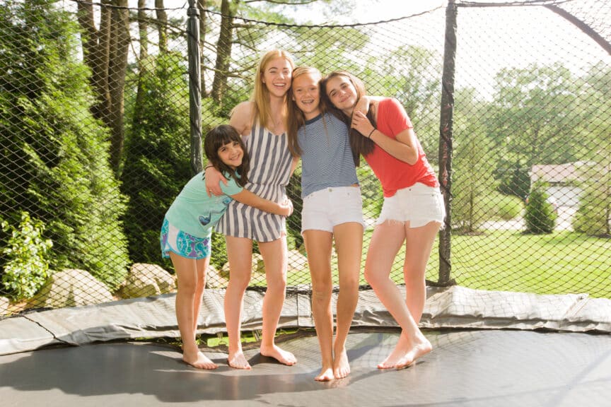 Sisters-hugging-on-a-trampoline-at-their-suburban-home