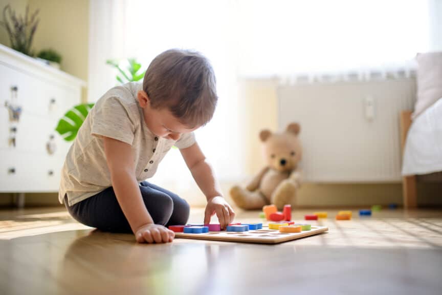 Small boy indoors at home playing on floor