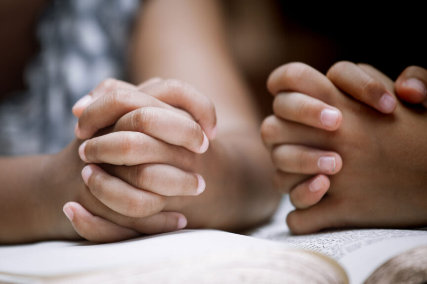 Two Little girl hands folded in prayer on a Holy Bible together