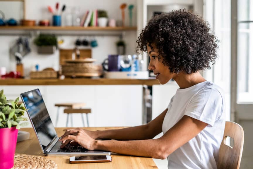 Woman using laptop at table at home