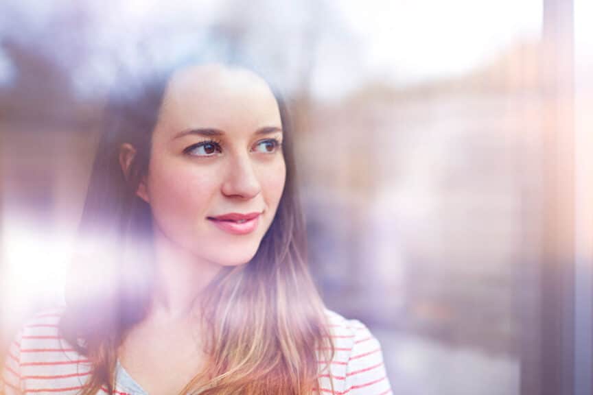 Young woman gazes thoughtfully through window