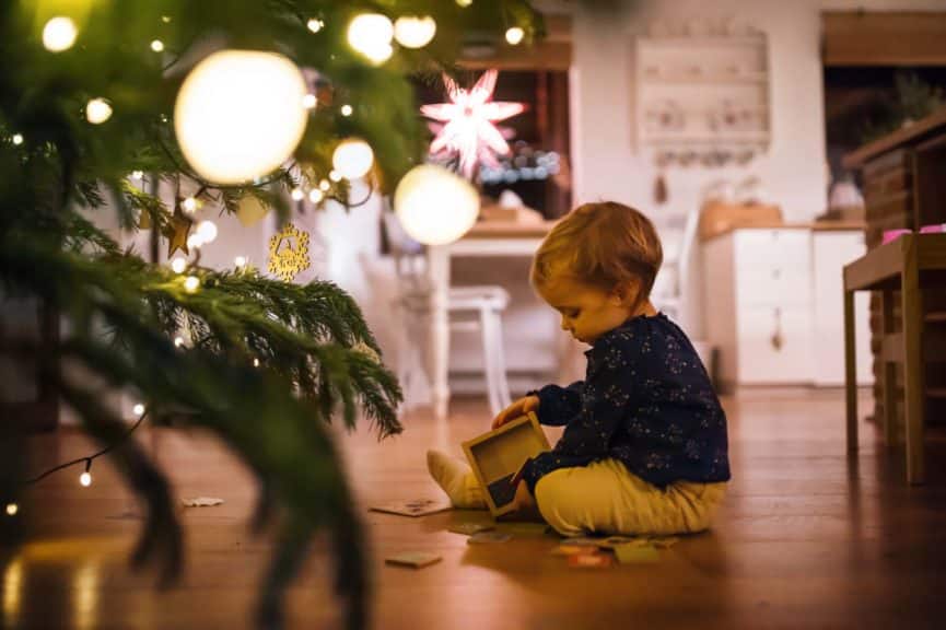 A small girl playing indoors on the floor at Christmas time