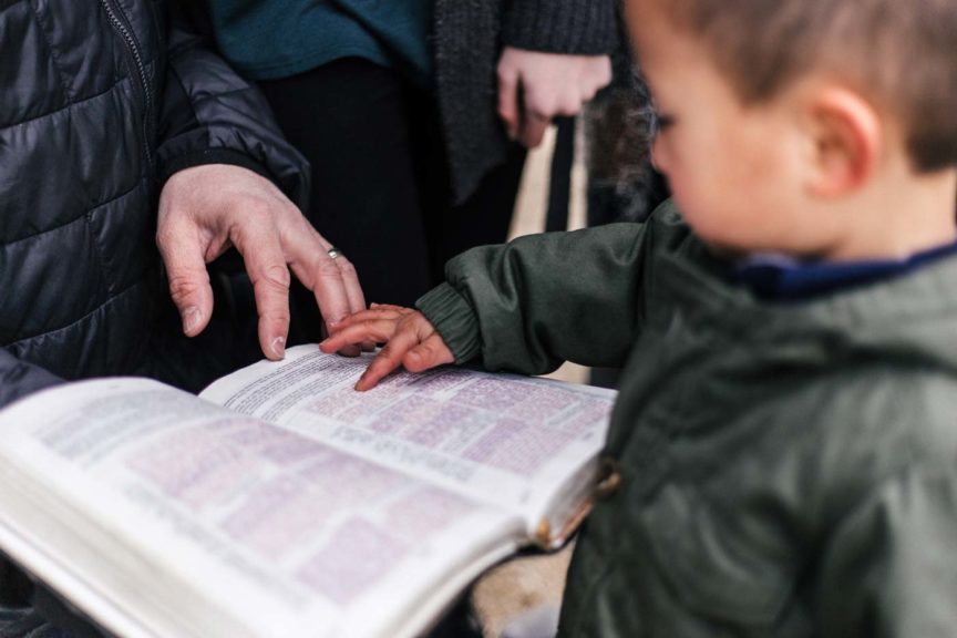 Boy and parent reading the bible together outside