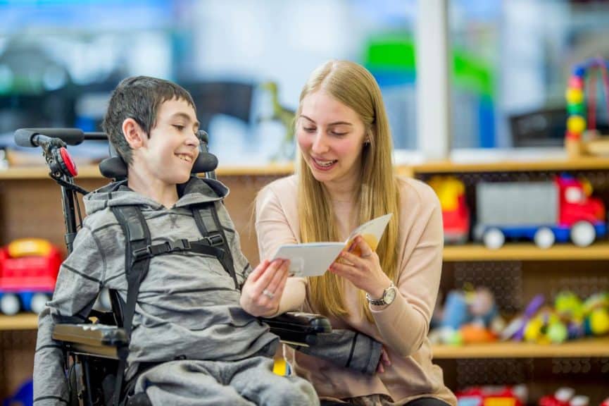 teacher reading to a boy in a wheelchair