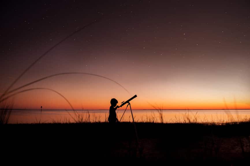 Silhouette de garçon regardant les étoiles à travers le télescope