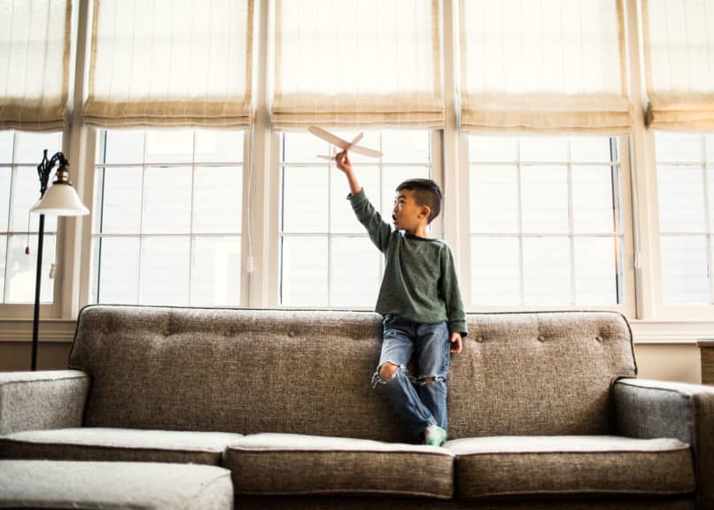 Boy playing with toy glider at home