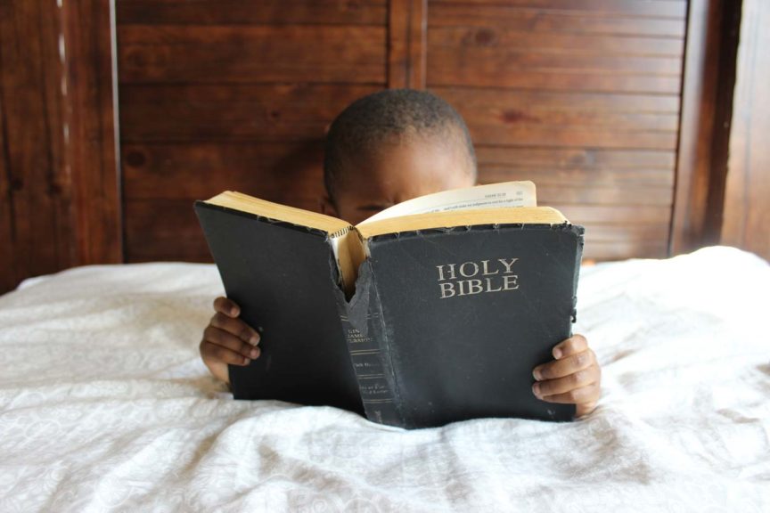 boy reading a Bible in bed