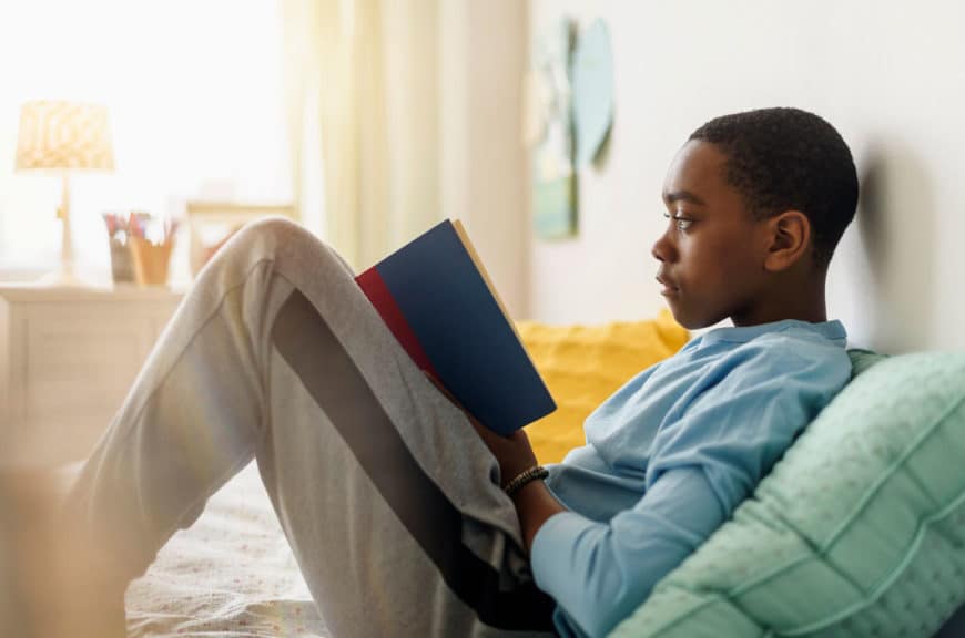 boy reading book on bed