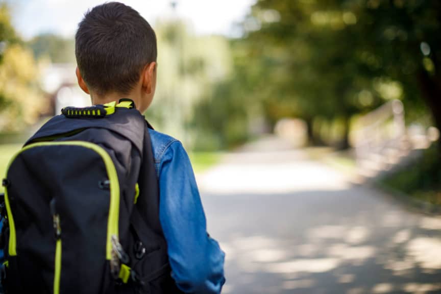 Teenage boy with school backpack going home from school