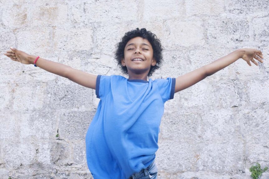 Boy standing with his arms outstretched, eyes closed