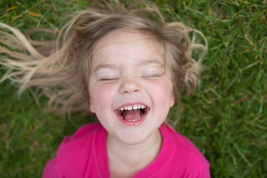 Child laughing while laying in the grass