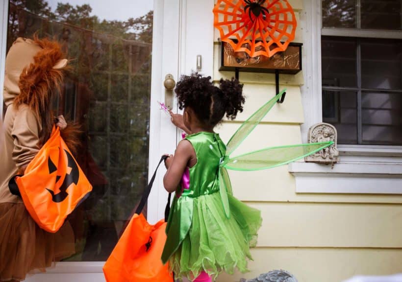 Children in Halloween costumes standing at doorway during trick or treating