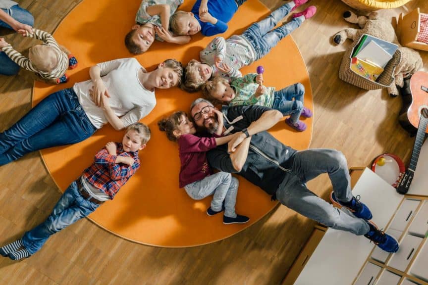 Children and teachers lying on carpet in kindergarten