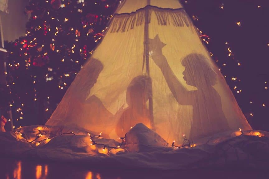 Children in tent in front of Christmas tree