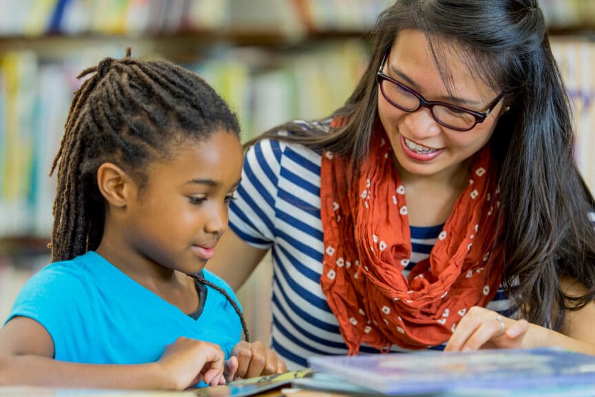 A children's ministry leader reads with a young girl.