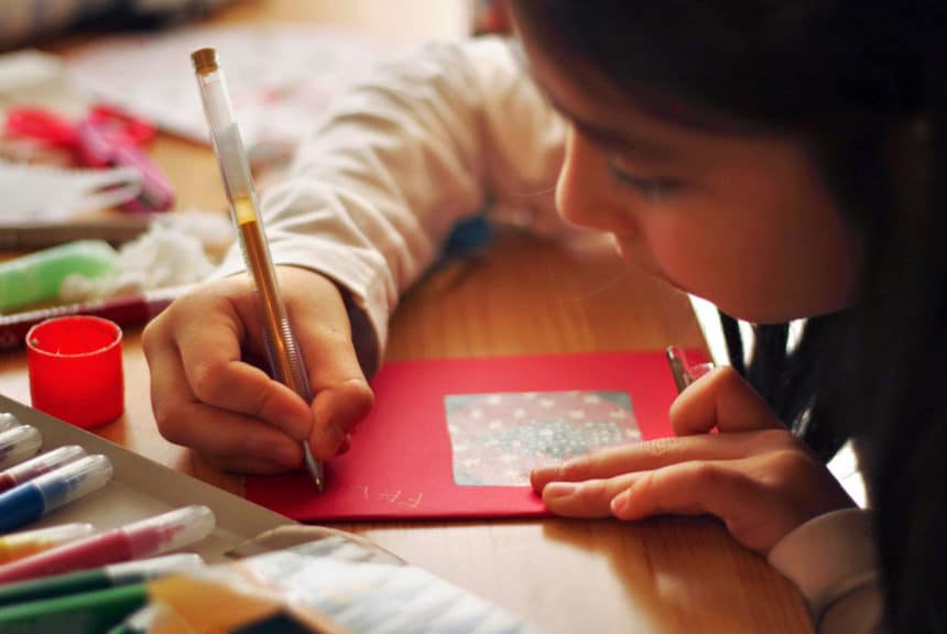 Close up of a girl's hand writing a postcard