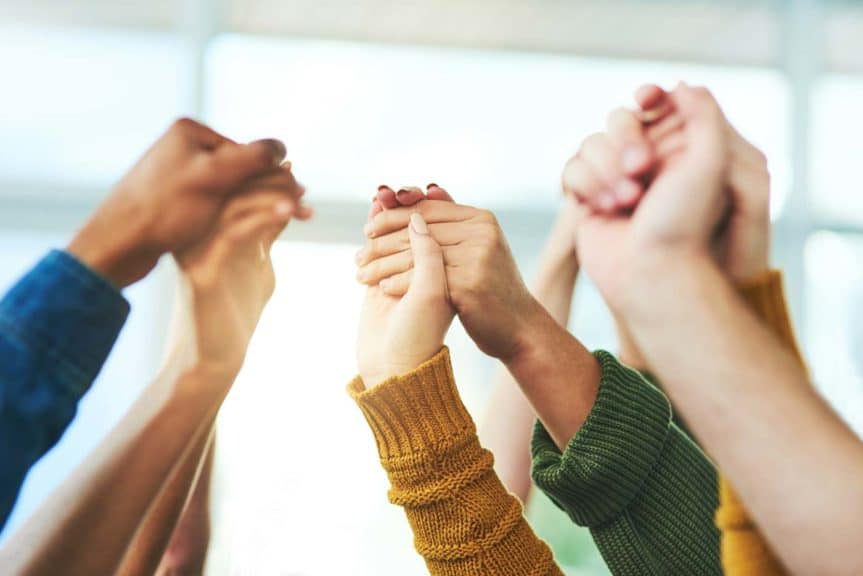 Closeup shot of a diverse group of people holding hands together in unity