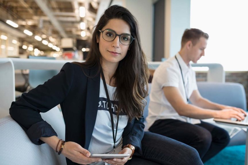 Portrait confident creative businesswoman using digital tablet in office lounge