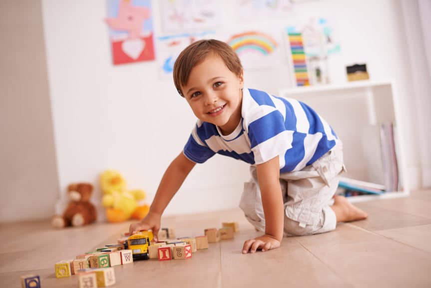 Portrait of a cute little boy playing with his building blocks and toys in his room