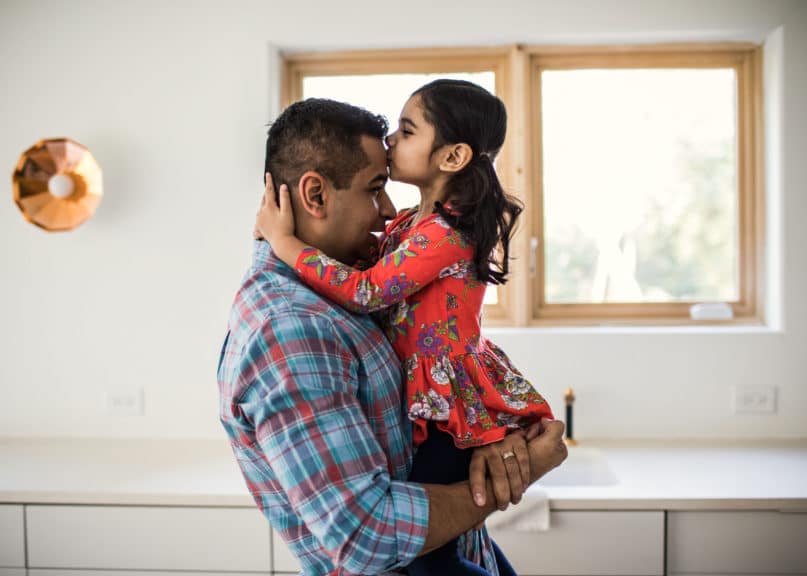 daughter kissing father at home