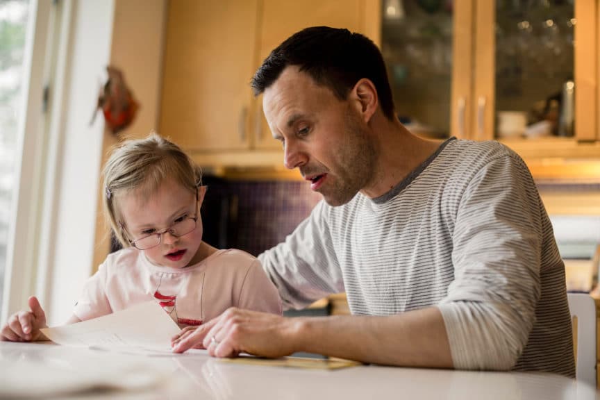 Father assisting handicapped daughter in studying at home