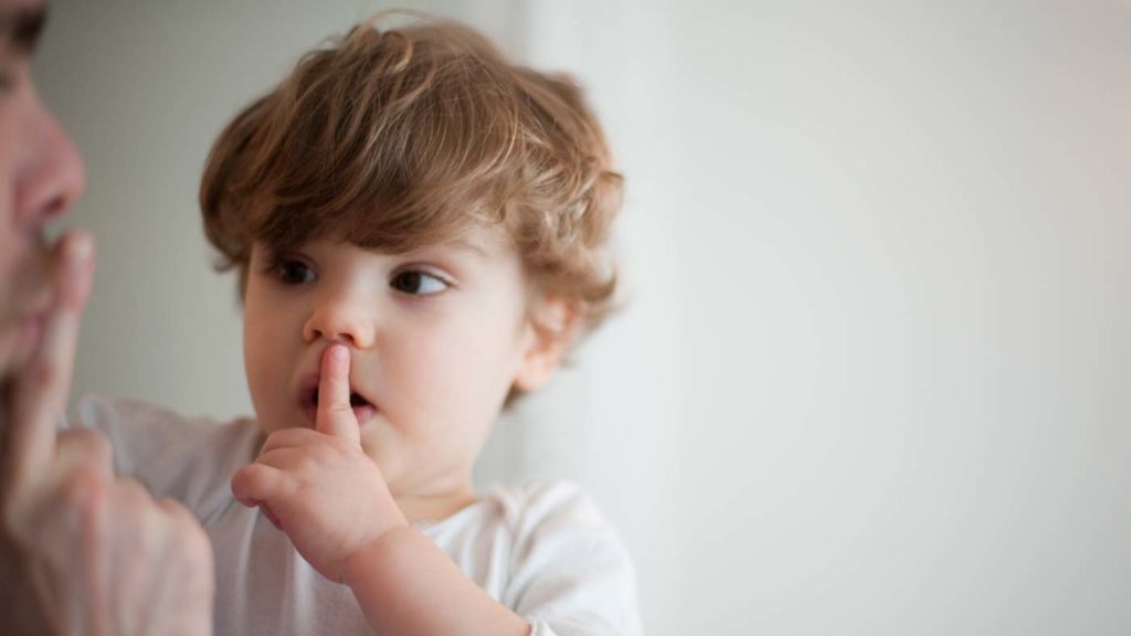 father hushing toddler boy