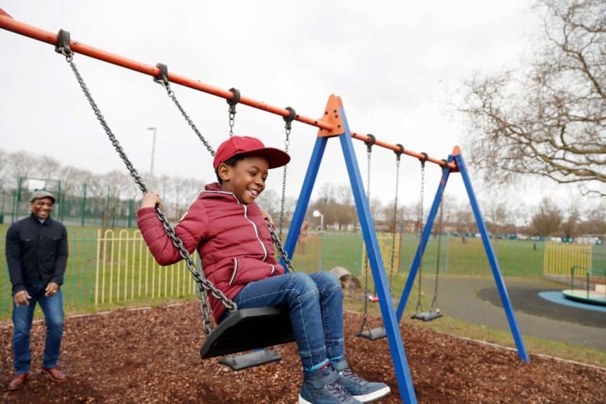 Father pushing son on swing at the park